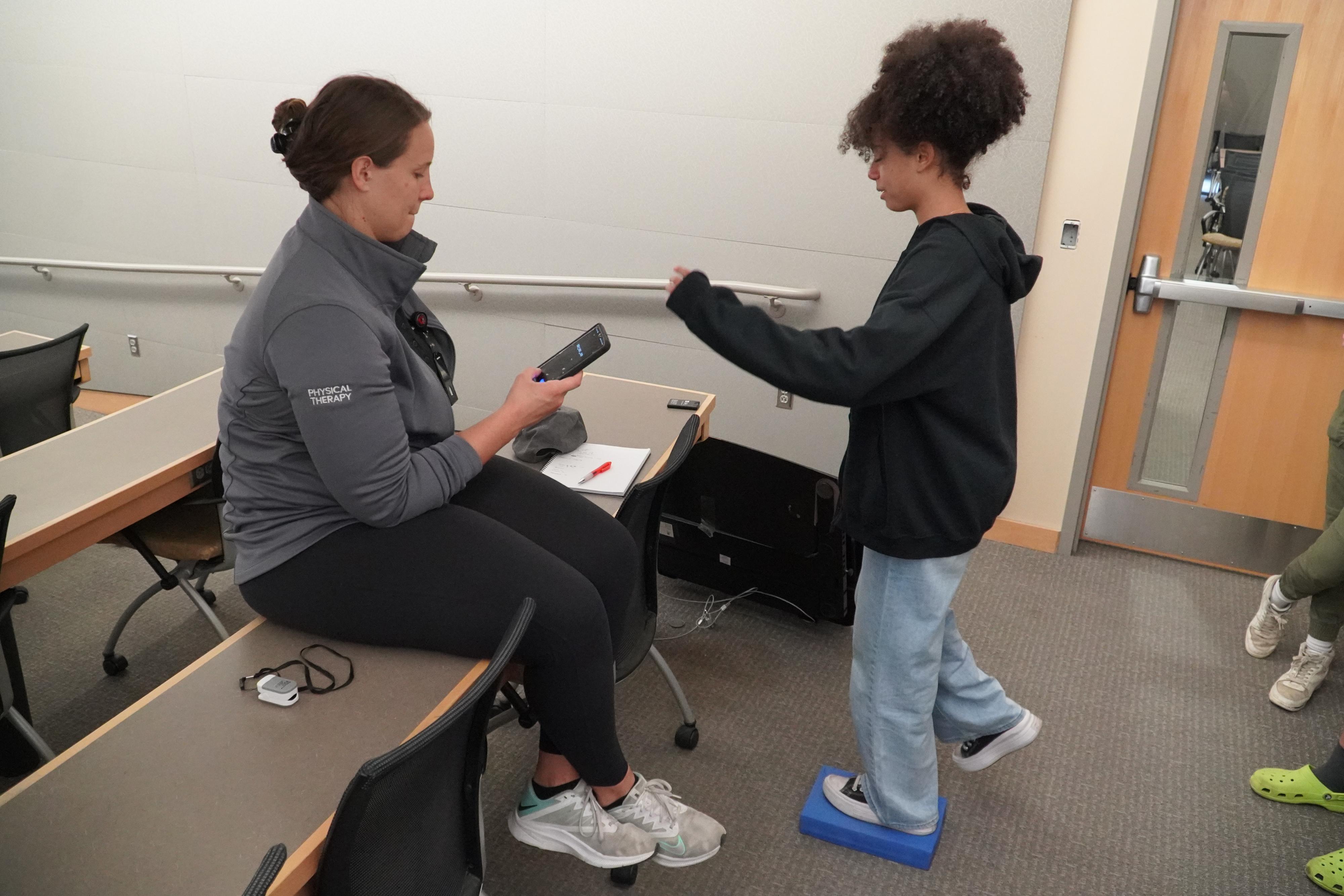 a Physical Therapy mentor times a student in a balancing activity at the Saturday Academy
