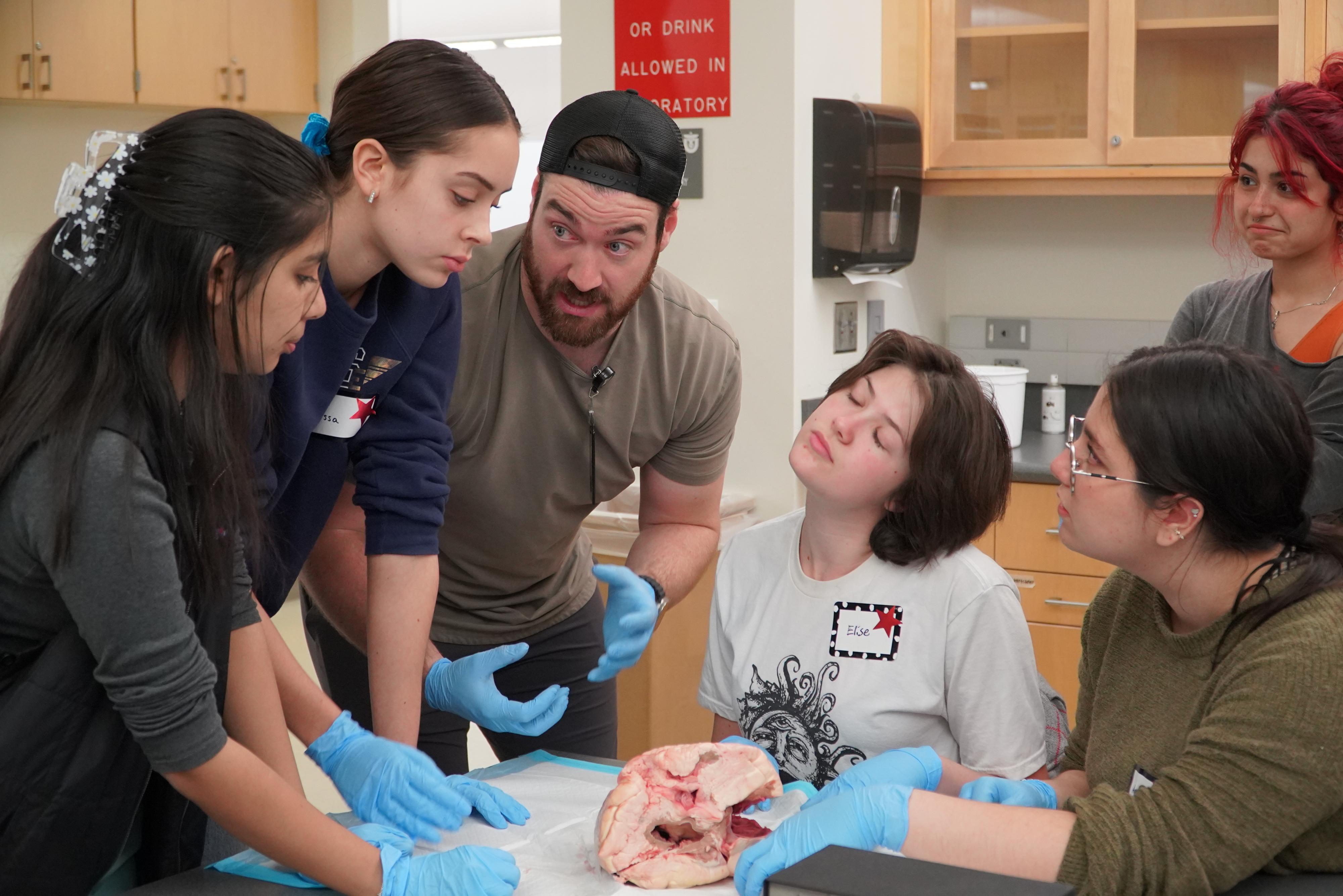 a School of Medicine mentor discusses a dissection activity with five students at the November Saturday Academy